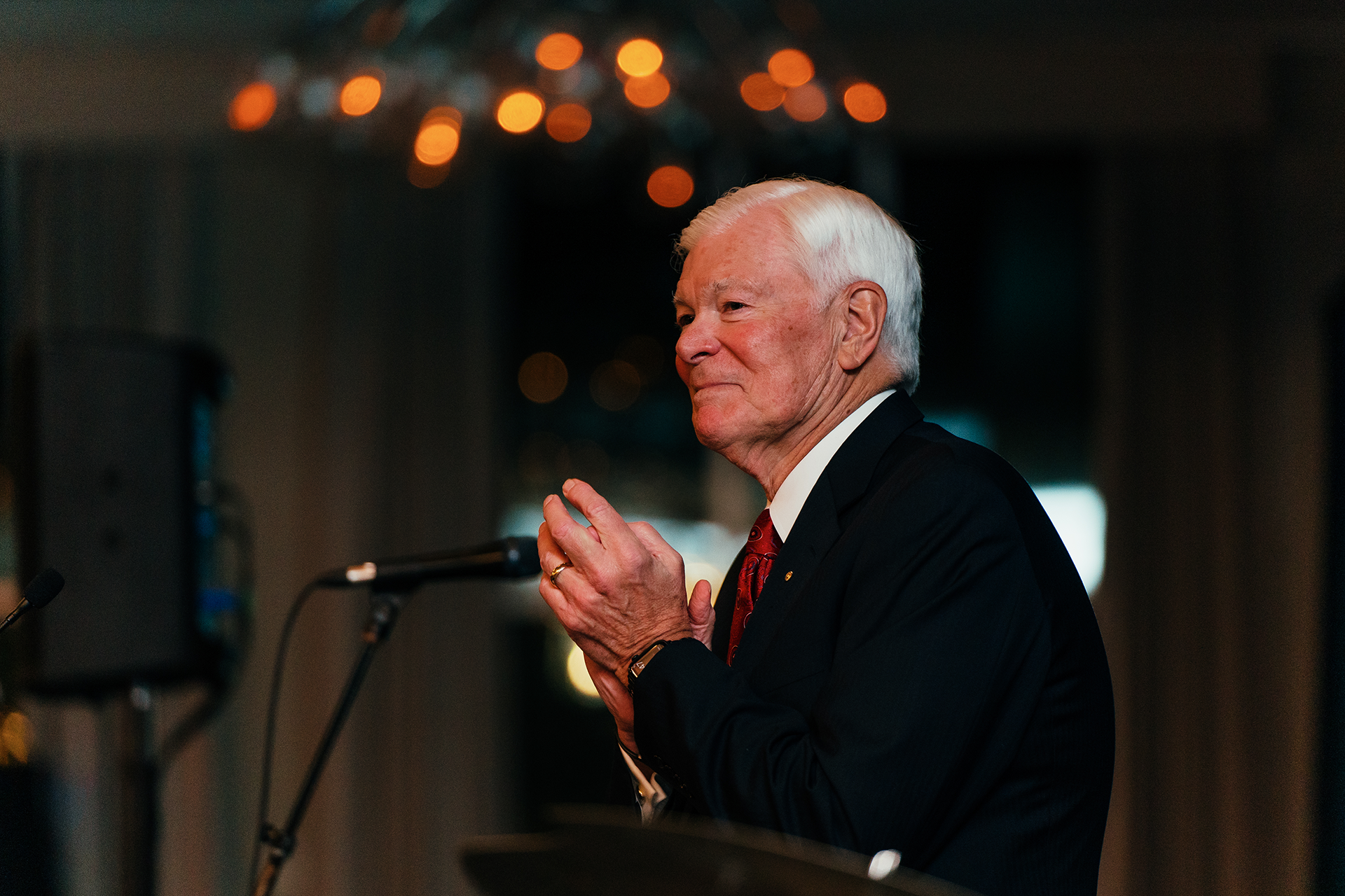 Man clapping while standing at a lecturn